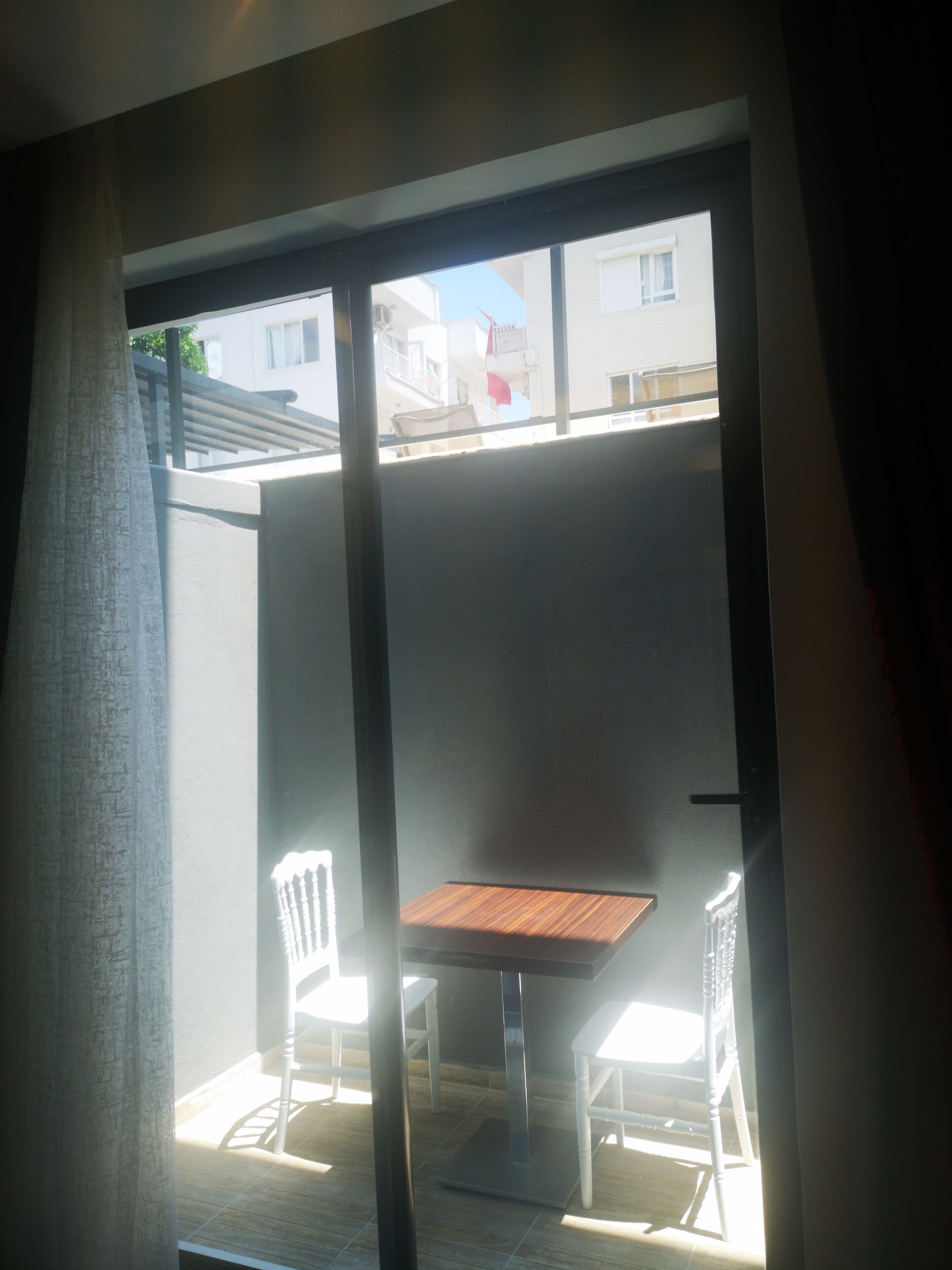 Una habitación con puerta corredera de vidrio que da a un patio exterior con mesa y sillas.