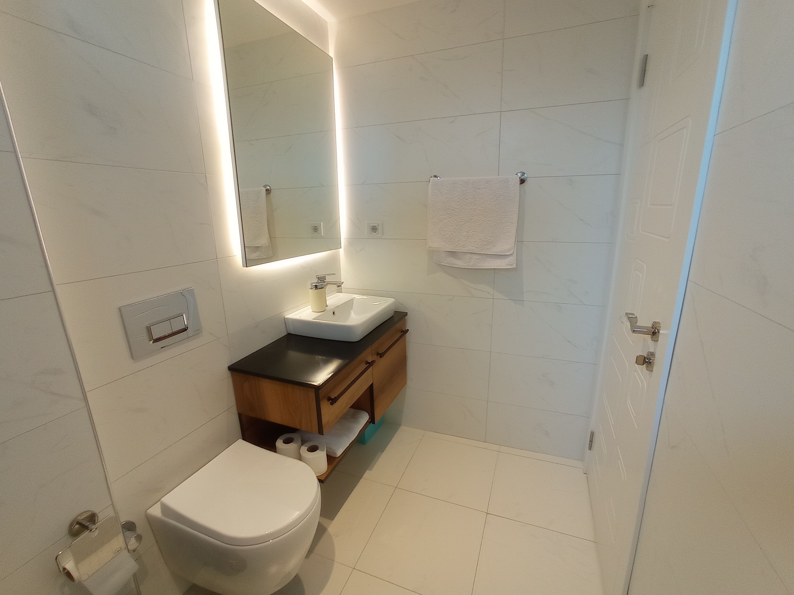 A modern bathroom with a toilet, sink, and mirror.