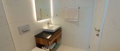 A modern bathroom with a toilet, sink, and mirror.