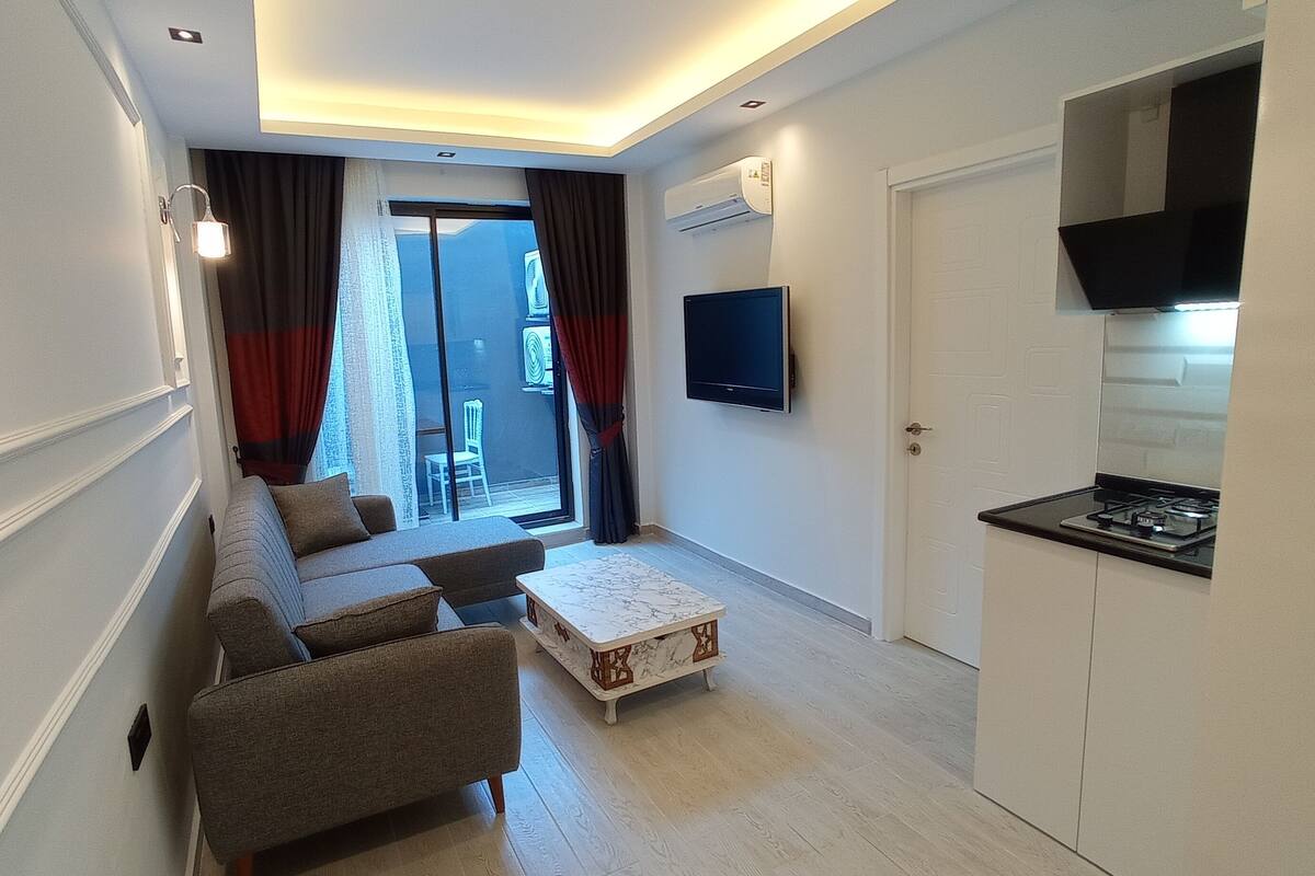 Ein modernes Wohnzimmer mit einer Couch, einem Couchtisch und einem an der Wand befestigten Fernseher.