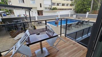 A rooftop patio with a pool, outdoor furniture, and a view of the surrounding buildings.