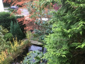 A serene garden with a pond, lush greenery, and a brick wall in the background. - Victorian Stable House with attractive vaulted ceiling , Southdowns. (Liss)