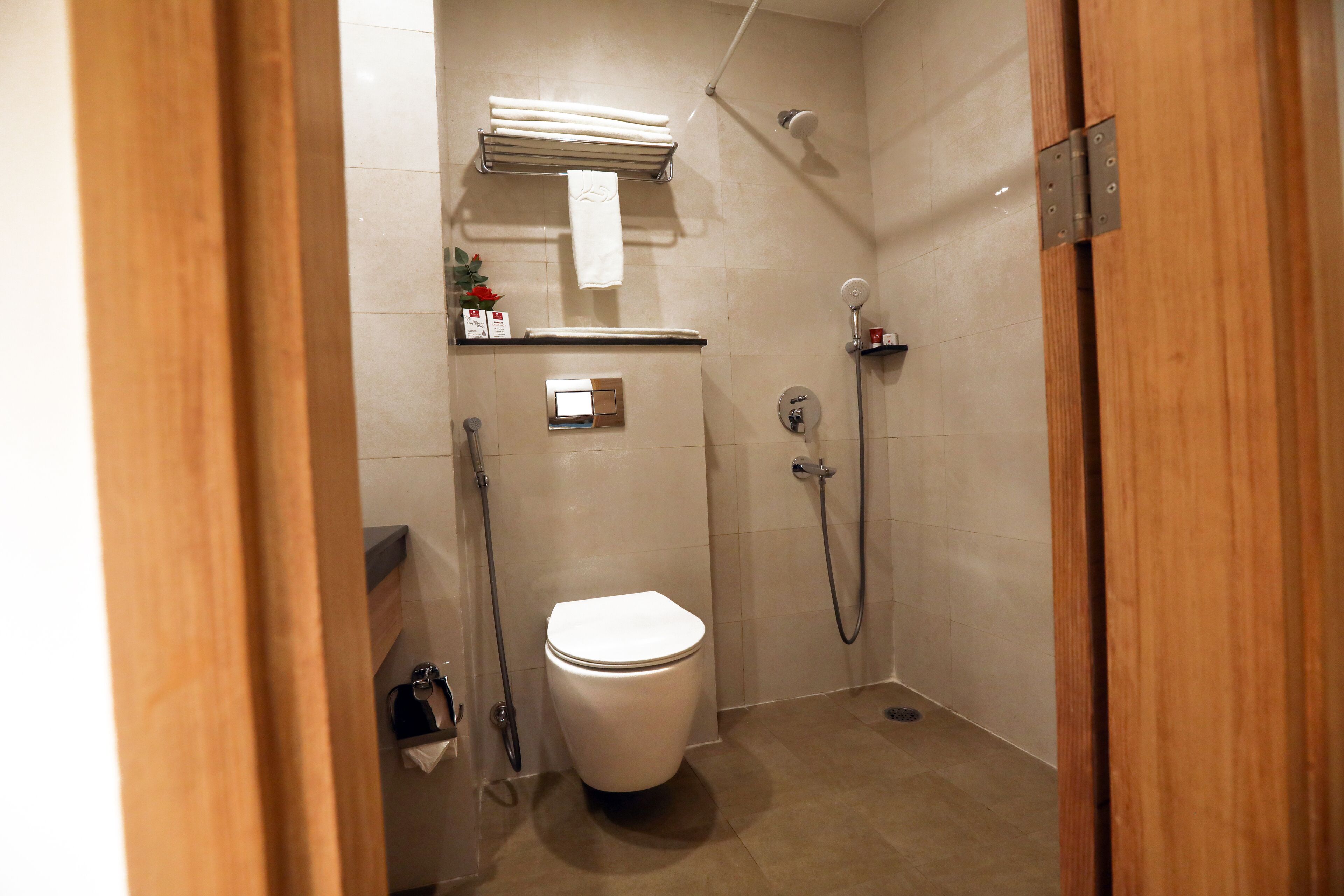 A small, modern bathroom with a toilet, a shower, and a towel rack.