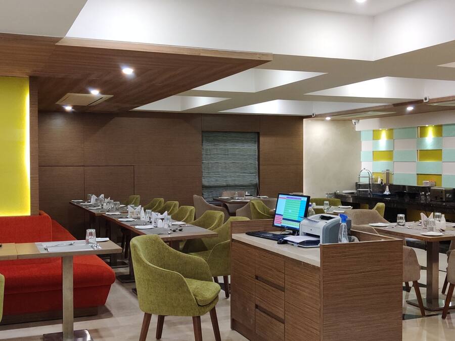 A modern dining area with multiple tables and chairs, a counter with a computer, and a vibrant wall design.