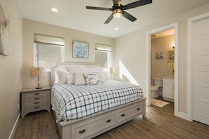 A bedroom with a bed, nightstands, a ceiling fan, and a bathroom visible through an open door.