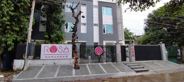 Un edificio moderno con un letrero que dice "ROSA GURUGRAM" y una entrada con portones.