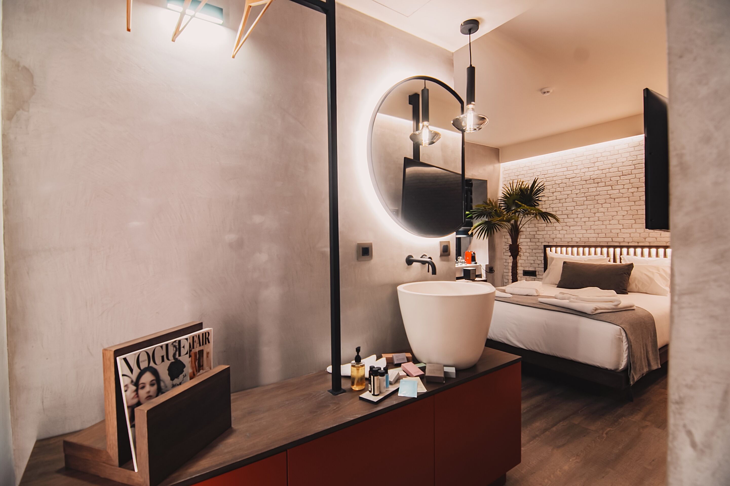 A modern bathroom with a large round mirror, a white sink, and a wooden vanity.