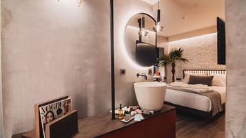 A modern bathroom with a large round mirror, a white sink, and a wooden vanity.