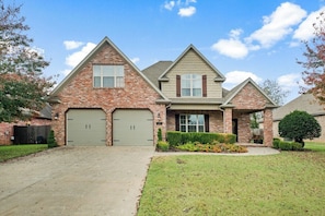 A two-story house with a brick facade, two garage doors, and a well-maintained lawn.