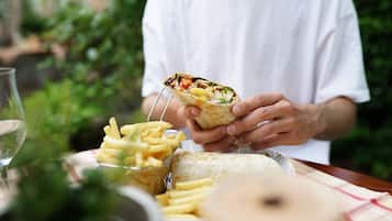 Una persona sosteniendo un wrap de verduras y una porción de papas fritas.