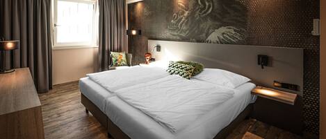 Ein modernes Schlafzimmer mit einem großen Bett, einem Schreibtisch und einer Wandleuchte.