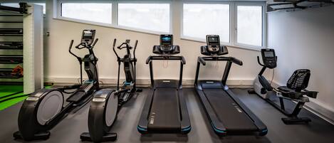 Un gimnasio con diversas máquinas de cardio, como elípticas, cintas de correr y una bicicleta estática.