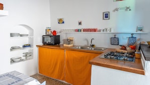 A kitchen with wooden cabinets, a gas stove, a microwave, and various kitchen utensils.