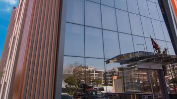 A modern hotel building with a reflective glass facade and vertical wooden slats on the side.