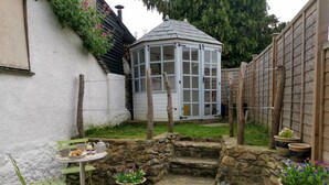 A garden with a gazebo, stone steps, and potted plants.