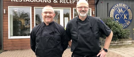 Two individuals standing in front of a building labeled "Golfshop Restaurant & Reception."