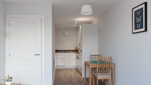 Een moderne keuken met witte kasten, een houten eettafel met stoelen en een hanglamp.