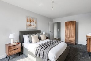 A bedroom with a bed, bedside tables, a wardrobe, and a painting on the wall.