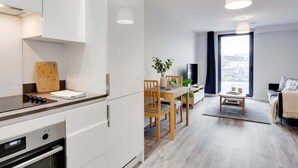 Une cuisine moderne avec des armoires blanches, une planche à découper en bois et un four encastré.