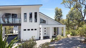 Ein modernes, zweistöckiges Haus mit Garage, großen Fenstern und einer überdachten Terrasse.