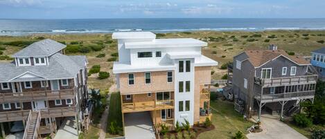 A coastal residential area with modern houses, including a two-story building with a balcony and a detached garage.