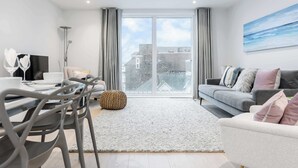 A modern living room with a dining area, large windows, and a city view. - Endless Summer - Spacious Living Space  Poole Quay (Poole)