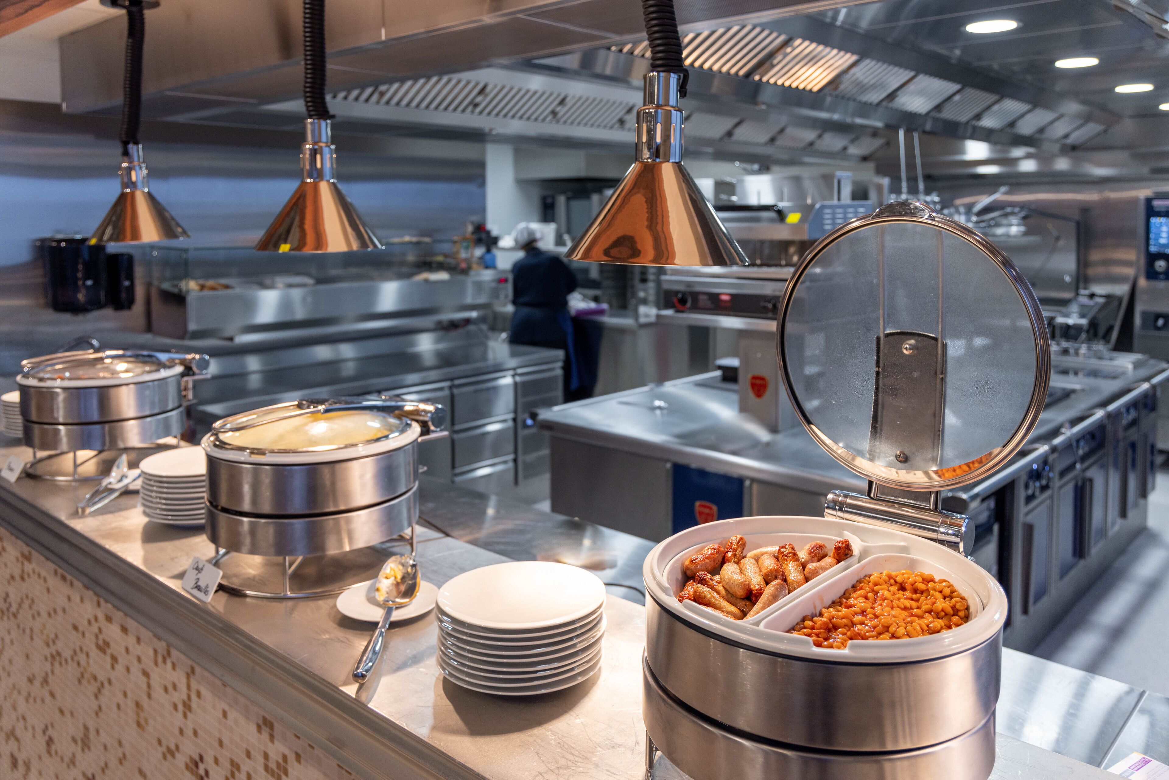 A buffet setup with various food containers and serving utensils.