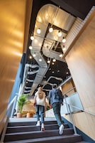 Una escalera de diseño moderno, barandillas de metal y techo con conductos y luminarias expuestos.