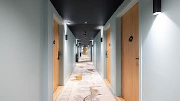 Un pasillo largo de hotel con puertas de madera y una alfombra estampada con motivos animales.