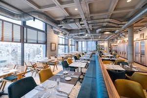 Un restaurante moderno con una barra larga, varias mesas y sillas.