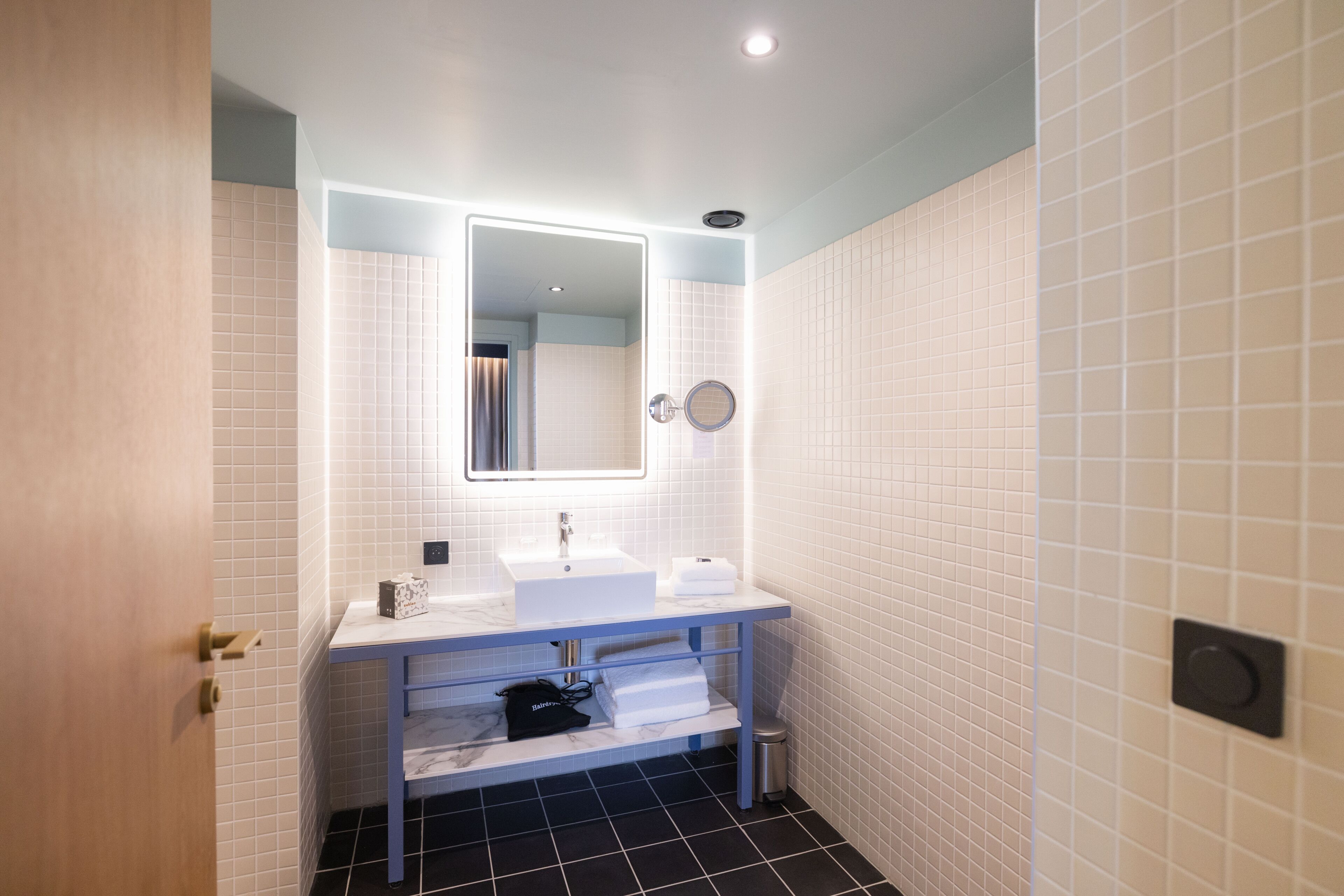 A modern bathroom with a white sink, a mirror, and a towel rack.