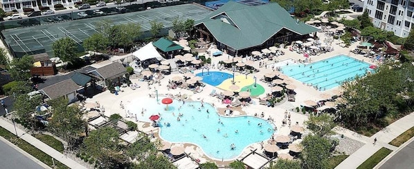 A resort with multiple swimming pools, sun loungers, and a large building with a green roof.