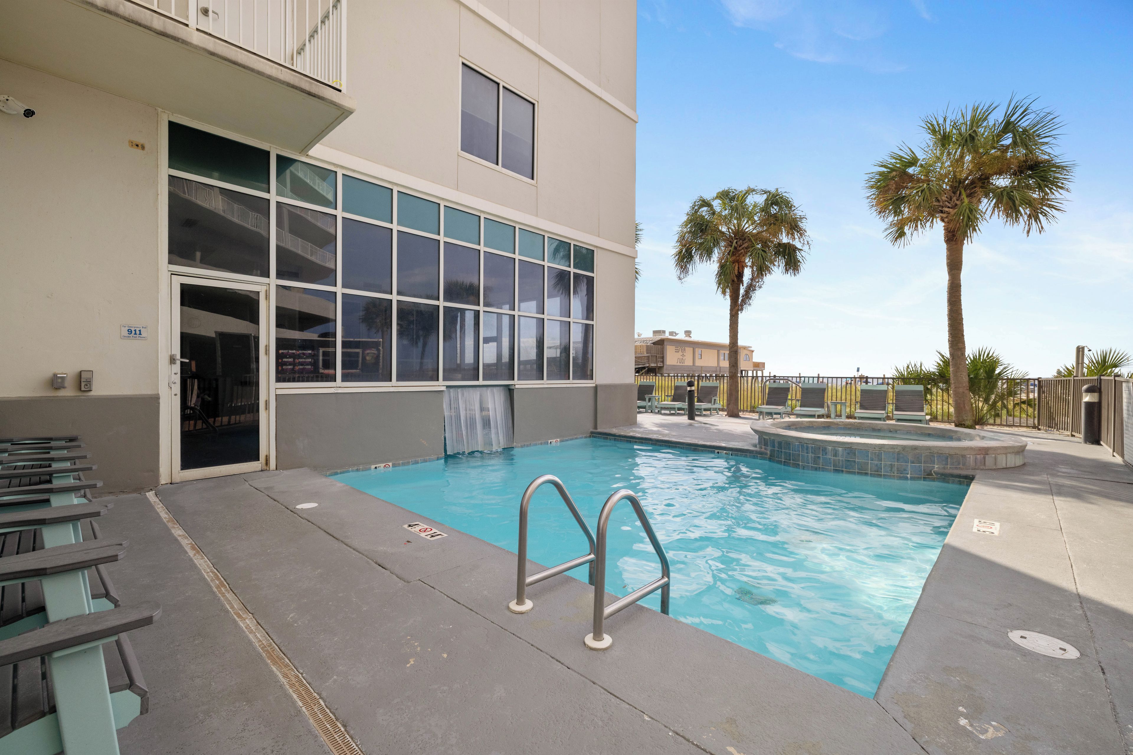 A swimming pool with a glass enclosure, a fire emergency stair, and outdoor seating.