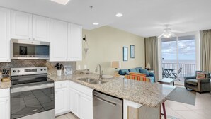 A modern kitchen with white cabinets, stainless steel appliances, and a granite countertop.