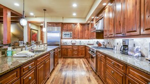 A spacious kitchen with wooden cabinets, granite countertops, stainless steel appliances, and a wooden floor.