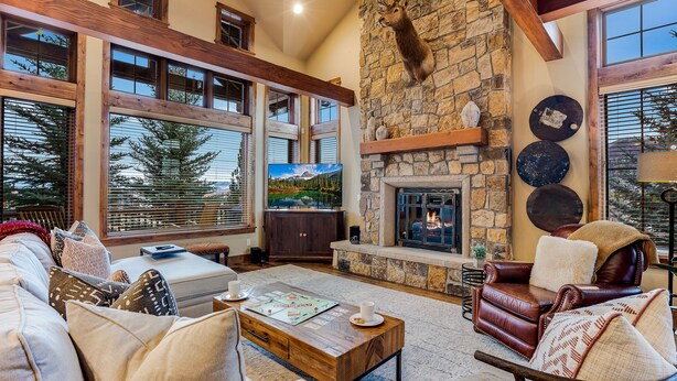 A spacious living room with a stone fireplace, large windows, and a cozy seating area.
