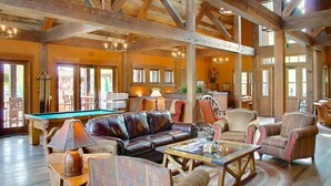 A spacious living area with a pool table, leather sofa, and comfortable seating.