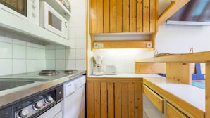 Une cuisine compacte équipée d’une cuisinière, d’un four à micro-ondes et d’une machine à café.