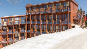 Un hôtel à plusieurs étages, doté de balcons, avec une piste de ski en premier plan.