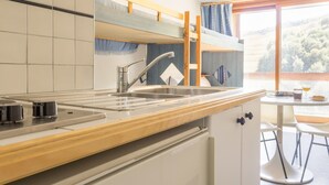 Cocina compacta con lavamanos, encimera de madera y vistas al exterior.