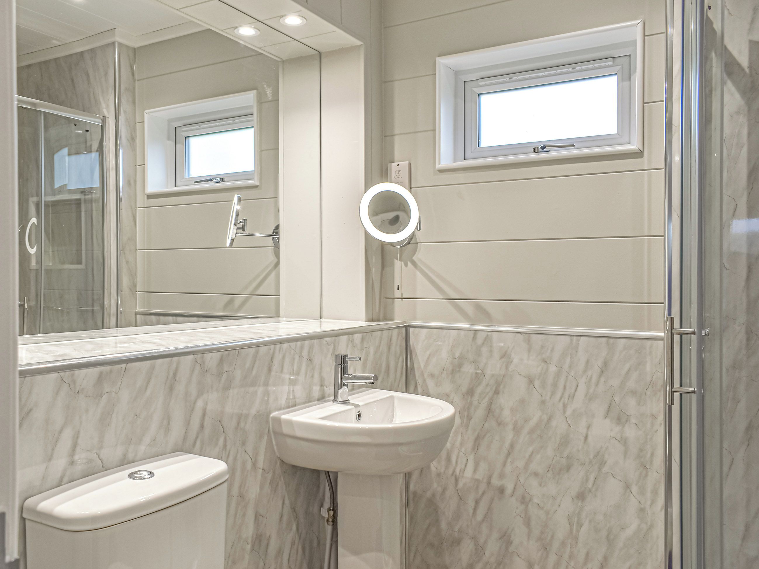 A bathroom with a marble sink, a toilet, a shower, and a window.