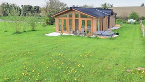 A modern house with a glass conservatory, a patio with outdoor furniture, and a well-maintained lawn. - Whitey Top Country Lodge (Pentridge)