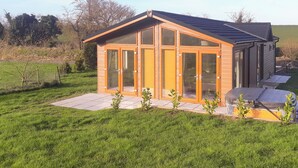 A modern house with a large glass door, a tiled patio, and a grassy yard. - Whitey Top Country Lodge (Pentridge)