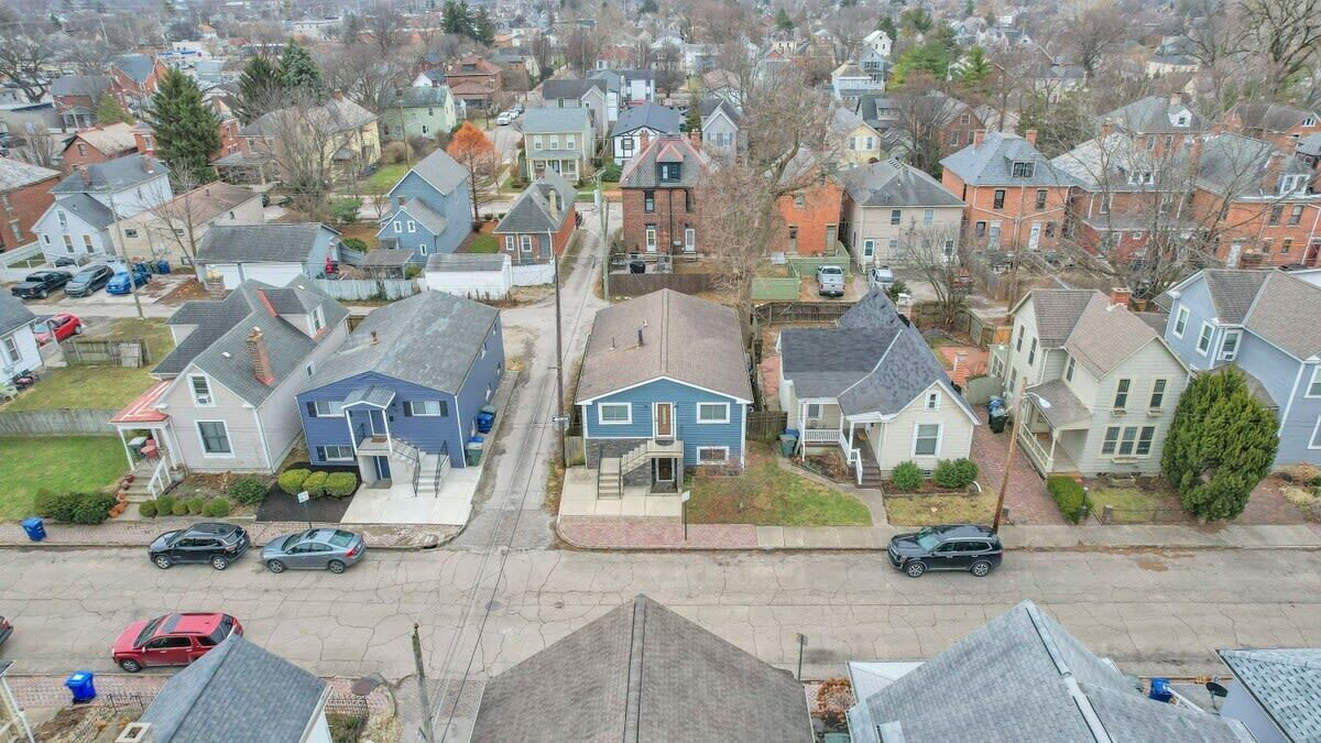 Luchtbeeld van een woonwijk met huizen, straten en geparkeerde auto's.