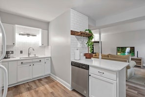 A modern kitchen with white cabinetry, a dishwasher, and a built-in island. - LowerFlat in GermanVillage - 3BR Pet | Yard | Park (Columbus)