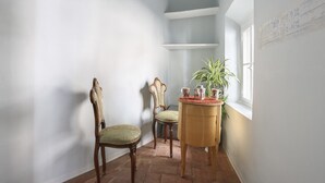A corner room with a wooden chair, a smaller chair, and a small table with a plant. - Lullaby Suite (Florence)
