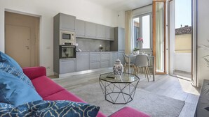 Un salon moderne avec un canapé, une table basse en verre et une cuisine en arrière-plan.