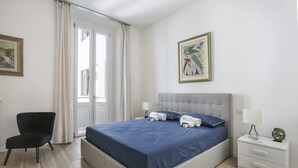 Une chambre à coucher avec un lit, une chaise, une table de chevet et un tableau accroché au mur.