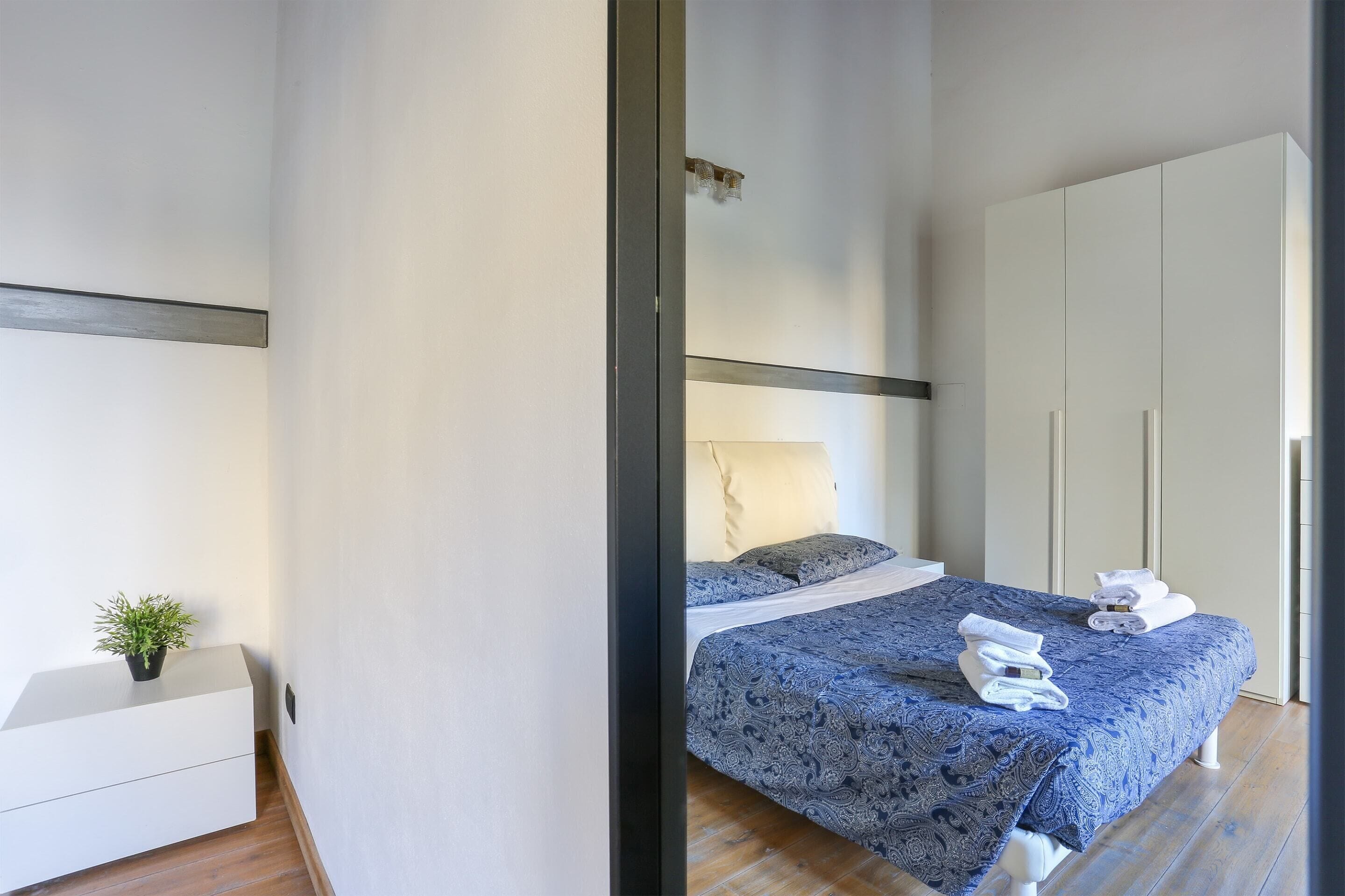 Une chambre à coucher moderne avec un lit, une table de chevet et une armoire.