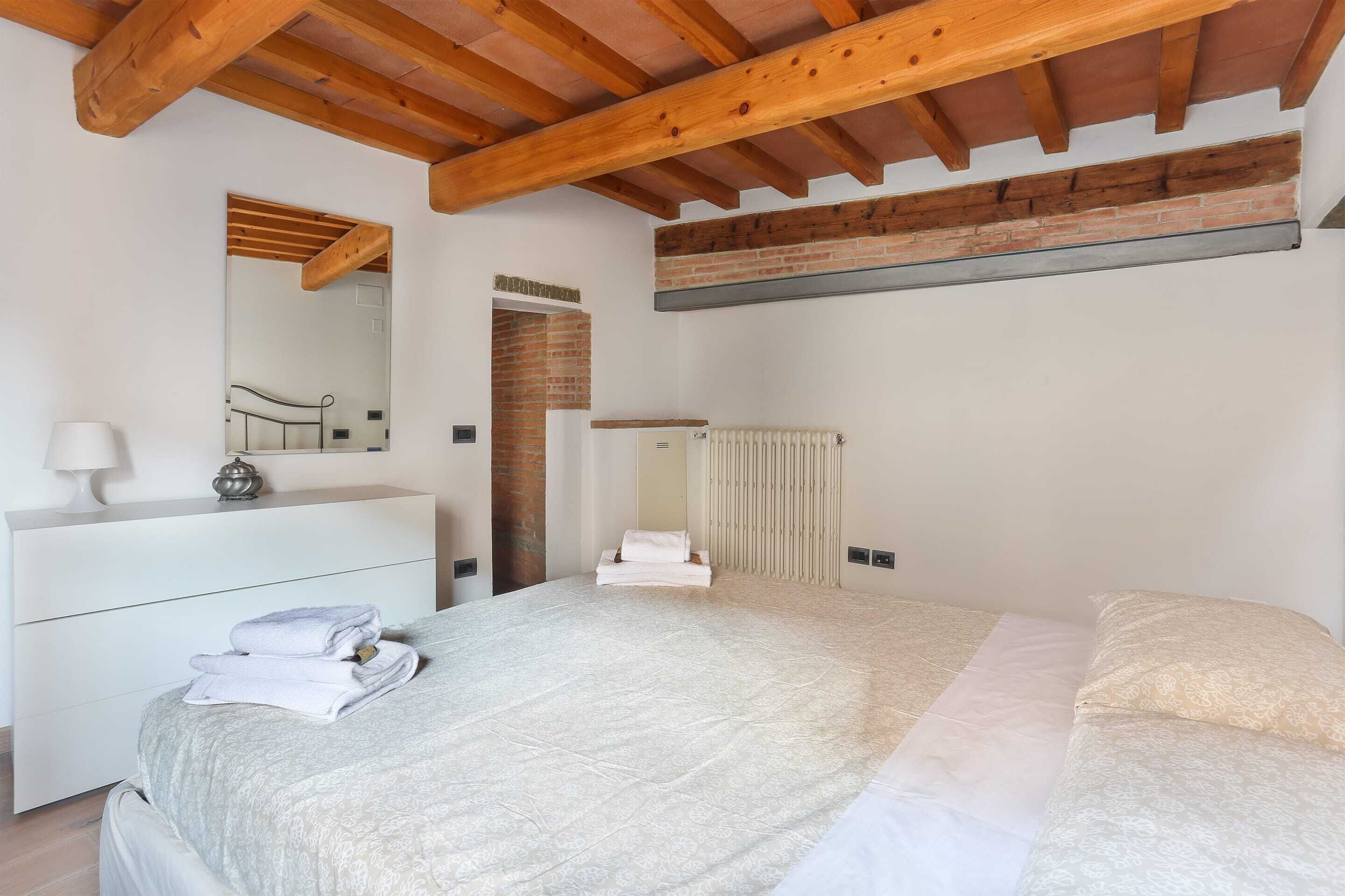 A bedroom with a bed, a dresser, a mirror, and a radiator.